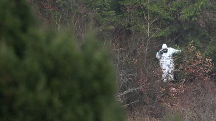 Ein Polizeibeamter steht in einem Waldstück.