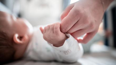 Ein Baby klammert sich an den Finger seiner Mutter. (Symbolbild)