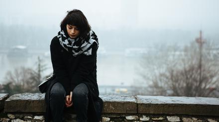 Girl sitting on a wall and having a tough time