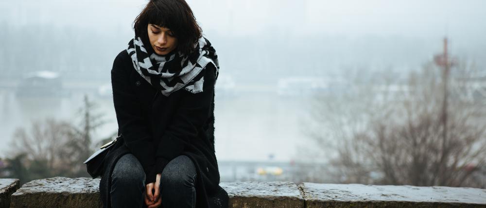 Girl sitting on a wall and having a tough time