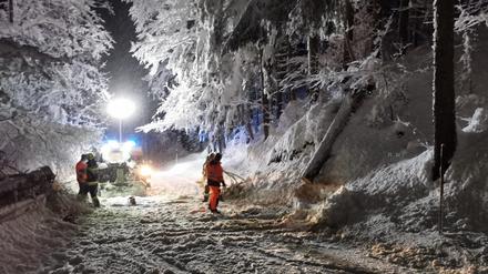 Ein Feuerwehrmann und Helfer sind nach starkem Schneefall im Einsatz. 