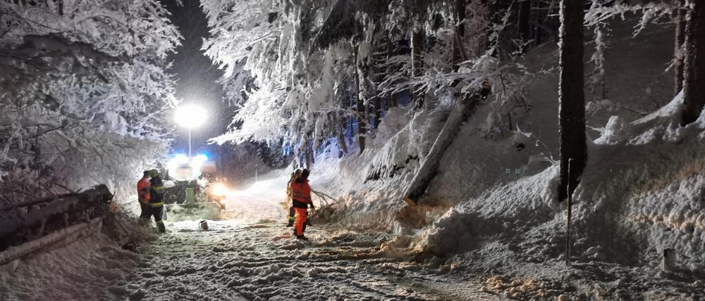 Ein Feuerwehrmann und Helfer sind nach starkem Schneefall im Einsatz.