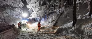 Ein Feuerwehrmann und Helfer sind nach starkem Schneefall im Einsatz. 