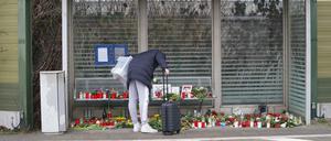 Eine Reisende schaut sich die Blumen, Kerzen und verschiedene Bilder im Wartehäuschen am Bahnhof Brokstedt zum Gedenken an die Opfer der Messerattacke an.