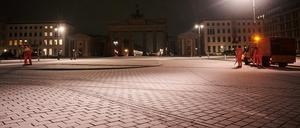 Mitarbeiter der Stadtreinigung BSR arbeiten am Montagmorgen bei Schnee vor dem Brandenburger Tor.