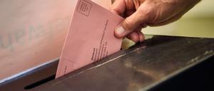 Ein Wähler wirft seinen ausgefüllten Wahlzettel in einem Wahllokal im Stadtteil Charlottenburg-Wilmersdorf in Berlin in eine Wahlurne.