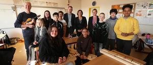 Musiker Thomas Kretschmer von der Kammerakademie Potsdam (KAP), KAP-Geschäftsführer Alexander Hollensteiner, Bildungsministerin Britta Ernst (SPD) sowie Schulleiterin Amrei Dettbarn (v.l.) sowie Schüler und Schülerinnen der 6b freuen sich über das Tandem-Musikprojekt an der Grundschule am Priesterweg.