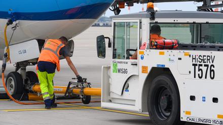 ARCHIV - 14.07.2021, Brandenburg, Schönefeld: Ein Mitarbeiter der WISAG Aviation koppelt auf dem Vorfeld des Flughafen BER ·Willy Brandt· ein Push-Back-Fahrzeug mit einem Flugzeug der KLM.  Erster Durchbruch bei den Tarifverhandlungen am Hauptstadtflughafen BER: Die Beschäftigten der Bodenverkehrsdienste erhalten laut der Gewerkschaft Verdi mehr Geld. (zu dpa «Verdi meldet Einigung mit Bodendienstleistern am Flughafen BER») Foto: Soeren Stache/dpa-Zentralbild/dpa +++ dpa-Bildfunk +++