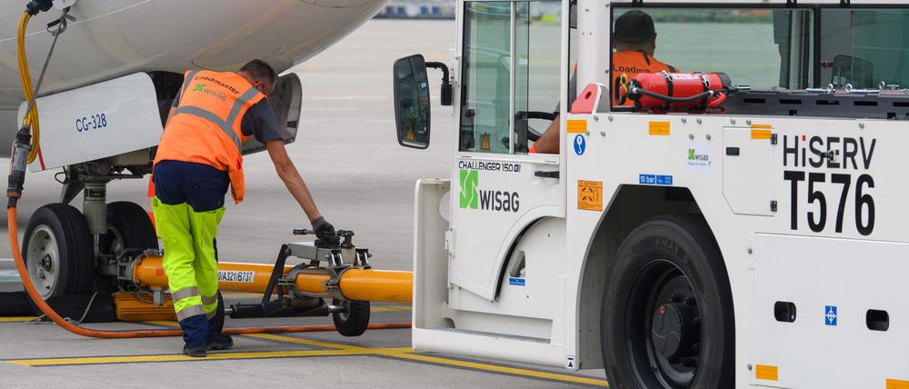 ARCHIV - 14.07.2021, Brandenburg, Schönefeld: Ein Mitarbeiter der WISAG Aviation koppelt auf dem Vorfeld des Flughafen BER ·Willy Brandt· ein Push-Back-Fahrzeug mit einem Flugzeug der KLM. Erster Durchbruch bei den Tarifverhandlungen am Hauptstadtflughafen BER: Die Beschäftigten der Bodenverkehrsdienste erhalten laut der Gewerkschaft Verdi mehr Geld. (zu dpa «Verdi meldet Einigung mit Bodendienstleistern am Flughafen BER») Foto: Soeren Stache/dpa-Zentralbild/dpa +++ dpa-Bildfunk +++