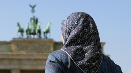 Eine muslimische Frau mit Kopftuch vor dem Brandenburger Tor in Berlin. 