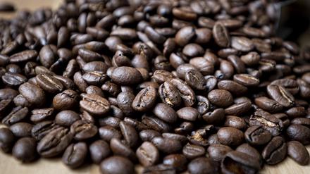 Geröstete Kaffeebohnen liegen auf einem Tisch. 