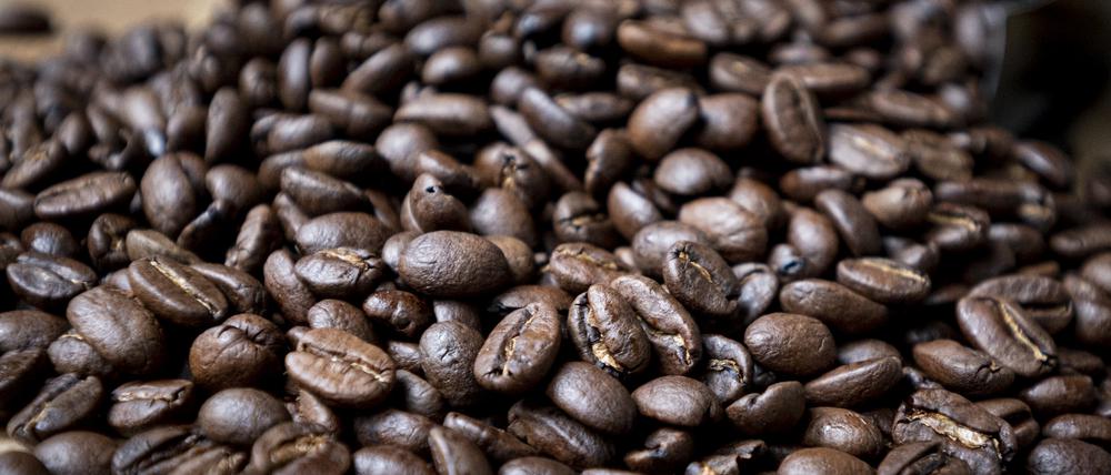 Geröstete Kaffeebohnen liegen auf einem Tisch. 