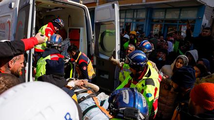 Rettungskräfte bringen die aus den Trümmern gerettete Frau in einen Krankenwagen.