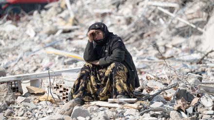 dpatopbilder - 11.02.2023, Türkei, Antakya: Eine Frau sitzt zwischen den Trümmern und beobachtet die Bergung von Opfern. Noch immer werden tausende Opfer unter den Trümmern vermutet. Helferteams aus der ganzen Welt sind im Katastrophengebiet im Einsatz. Foto: Boris Roessler/dpa +++ dpa-Bildfunk +++