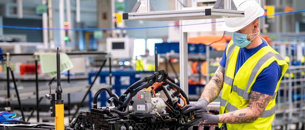Ein Mitarbeiter von VW arbeitet am Unterboden mit der Batterie. Der branchenweit drohende Stellenabbau fällt unter dem Strich niedriger aus, je größer die Chancen für neue Arbeitsplätze in der elektromobilen Autowelt eingeschätzt werden, zeigen Studien.
