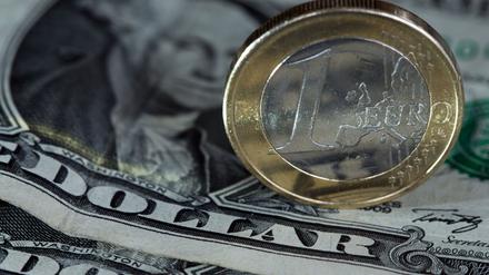 Eine Euro-Münze liegt auf einem Dollar-Geldschein. (Symbolbild)