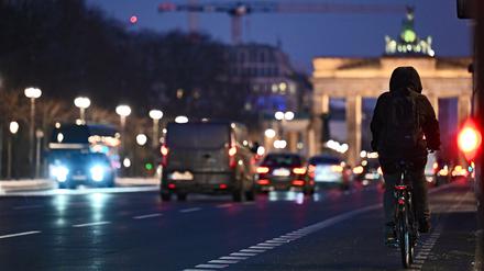 Ein Radfahrer fährt bei beginnender Dämmerung auf dem Fahrradweg in Richtung Brandenburger Tor.