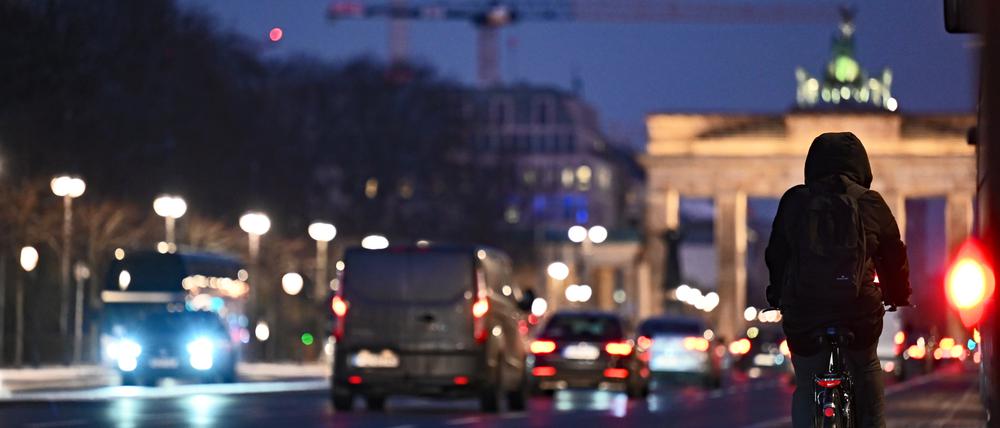 Ein Radfahrer fährt bei beginnender Dämmerung auf dem Fahrradweg in Richtung Brandenburger Tor.