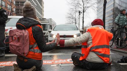 Klimaaktivisten sitzen mit ihren Händen zusammengeklebt auf einer Straße am Potsdamer Platz.