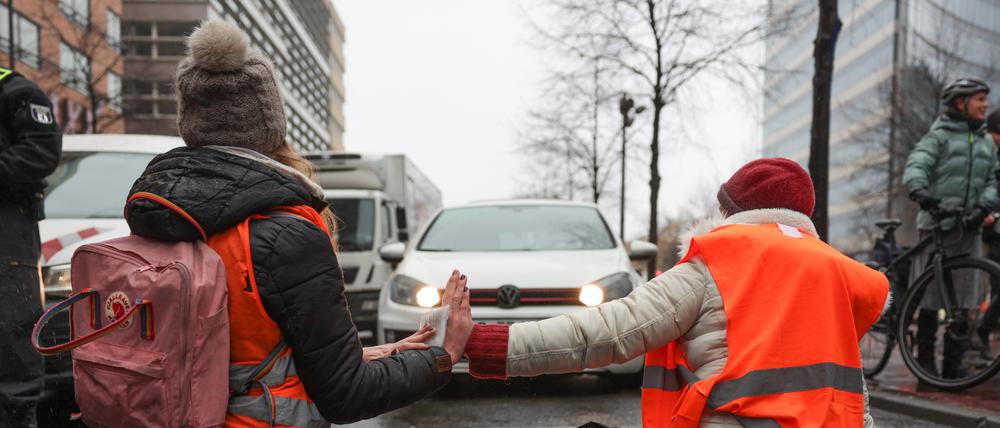 Klimaaktivisten sitzen mit ihren Händen zusammengeklebt auf einer Straße am Potsdamer Platz.