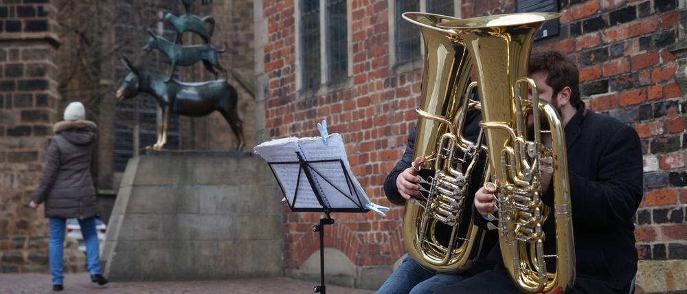 Vor dem Wahlprüfungsgericht verlor die AfD mit Pauken und Trompeten. Zwei Straßenmusiker mit Tuba sitzen neben der Bronzeplastik der Bremer Stadtmusikanten am Rande des Bremer Rathauses. (Symbolbild)