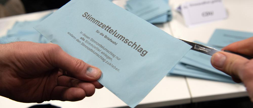Ein Wahlhelfer öffnet im City Cube nach der wiederholten Wahl den Stimmzettelumschlag eines Briefwählers.