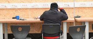 Ein Geflüchteter ist in einem Zelt der Flüchtlingsunterkunft mit seinem Smartphone beschäftigt.
