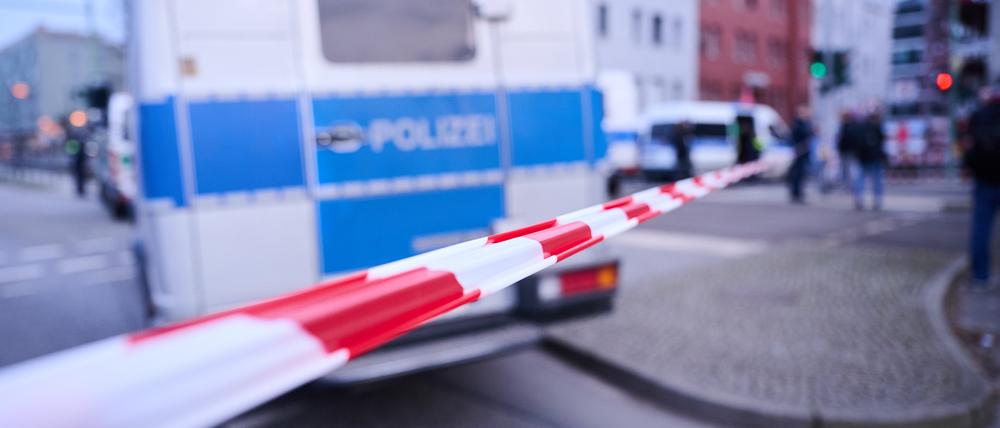PRODUKTION - 16.02.2023, Berlin: Nach einem ausgelösten Amokalarm in einem Berliner Jobcenter stehen Einsatzfahrzeuge hinter der Absperrung an der Landsberger Allee. Einsatzkräfte befinden sich im Gebäude. Die Polizei hat nach längerer Suche nichts Auffälliges gefunden. Foto: Annette Riedl/dpa +++ dpa-Bildfunk +++