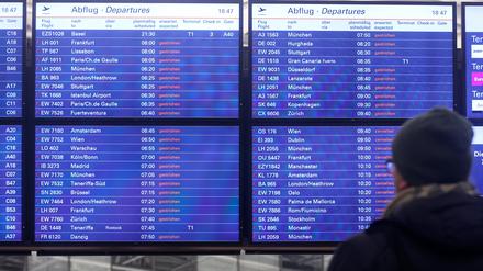 Ein Mann schaut am Flughafen Hamburg auf eine Anzeigentafel, auf der zahlreiche gestrichene Flüge angezeigt werden.