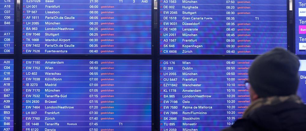 Ein Mann schaut am Flughafen Hamburg auf eine Anzeigentafel, auf der zahlreiche gestrichene Flüge angezeigt werden.