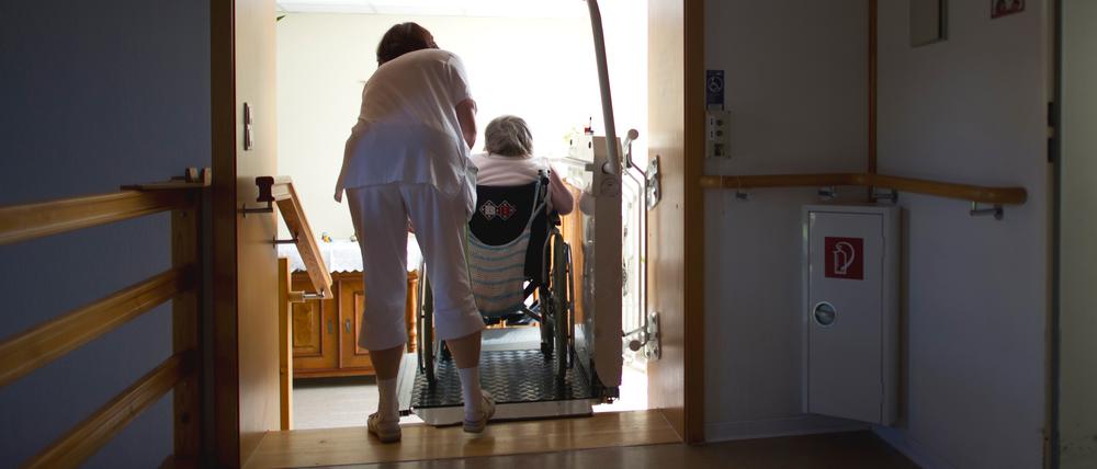 ARCHIV - Eine Pflegerin hilft einer Bewohnerin einer Altenpflegeheimes mit einer Rollstuhlhilfe eine Treppe hinauf, aufgenommen am 26.04.2012. Foto: Arno Burgi/dpa +++ dpa-Bildfunk +++