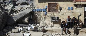 Menschen sitzen vor einem eingestürztem Gebäude im syrischen Jinderis.