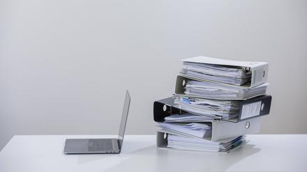 Symbolfoto zum Thema Digitalisierung in der Verwaltung . Ein Computer liegt neben einem Haufen Aktenordner. 