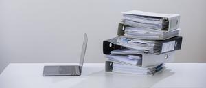 Symbolfoto zum Thema Digitalisierung in der Verwaltung . Ein Computer liegt neben einem Haufen Aktenordner. 
