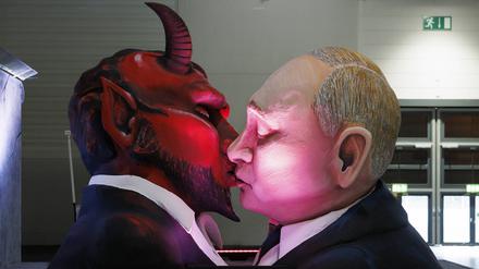 Russlands Präsident Wladimir Putin beim sozialistischen Bruderkuss mit dem Teufel beim Richtfest der Persiflagewagen und Karnevalswagen zum Kölner Rosenmontagszug 2023 in der Koelnmesse.