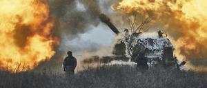 Ukrainische Soldaten stehen vor einem selbstfahrenden Artilleriefahrzeug, das in der Kälte bei Eis und Schnee an der Front im Gebiet Donezk abfeuert. 