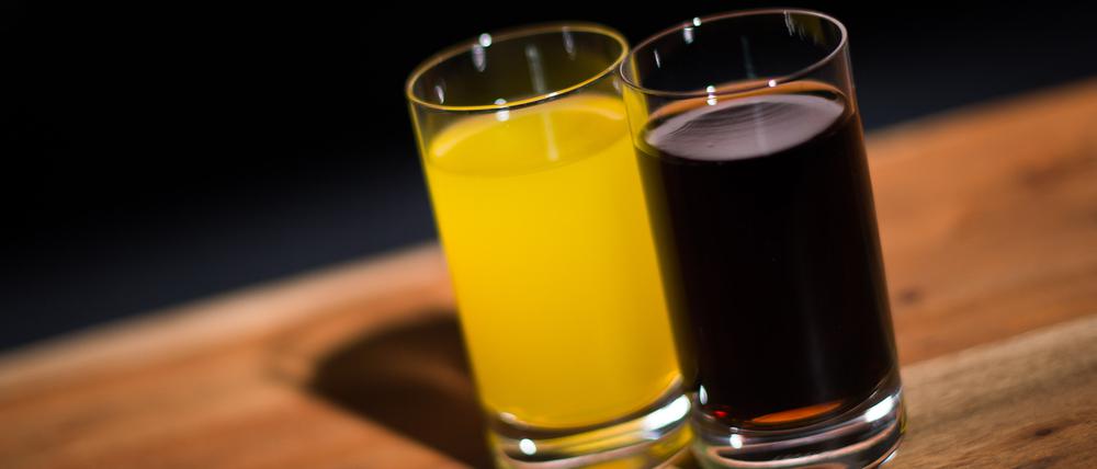 ARCHIV - 29.03.2016, Hamburg: ILLUSTRATION - Ein Glas mit Cola steht neben einem Glas mit Orangenlimonade. Verbraucherschützer und Gesundheitsexperten fordern verbindlichere Vorgaben und mehr Tempo, um zu weniger Zucker in Erfrischungsgetränken wie Cola oder Limonaden zu kommen. (zu dpa «Rufe nach mehr Tempo bei Zuckerreduktion in Limonaden») Foto: Lukas Schulze/dpa +++ dpa-Bildfunk +++