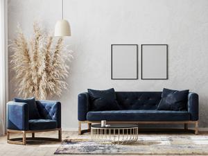 Ein modern eingerichtetes Wohnzimmer mit einem blauen Sofa und zwei blauen Sesseln vor einer grauen Wand (Symbolbild)