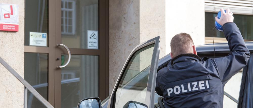 Ein Polizist vor seinem Auto.