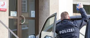 Ein Polizist vor seinem Auto.