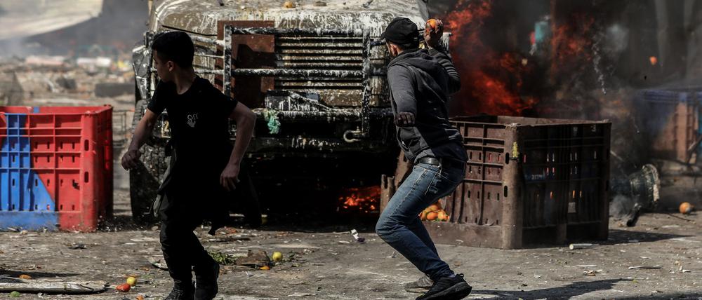 22.02.2023, Palästinensische Gebiete, Nablus: Palästinenser rennen während der Zusammenstöße im Westjordanland vor ein Fahrzeug der israelischen Armee. Foto: Ayman Nobani/dpa +++ dpa-Bildfunk +++