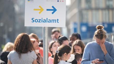 Flüchtlinge, darunter der größte Teil aus der Ukraine, und eine Helferin (r) stehen vor einer Außenstelle des Sachgebiets Flüchtlinge der Ausländerbehörde.
