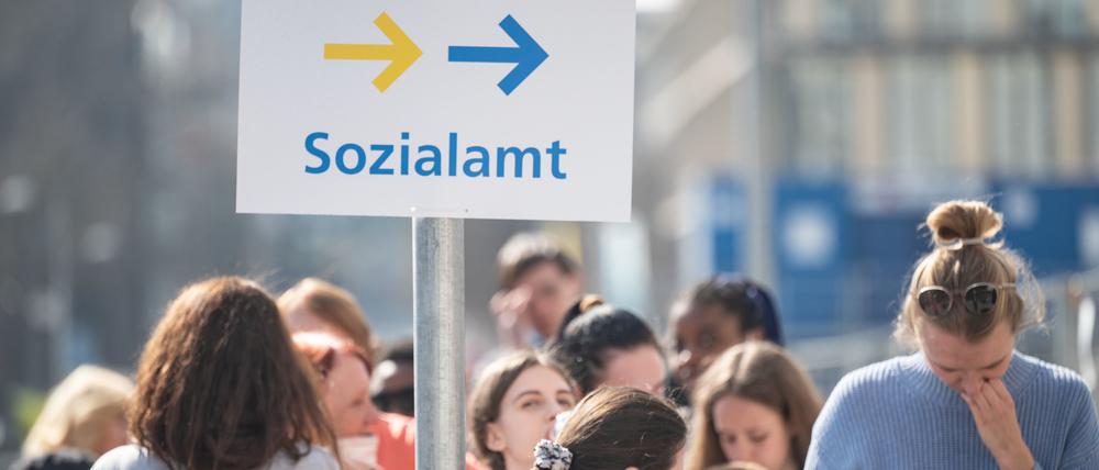 Flüchtlinge, darunter der größte Teil aus der Ukraine, und eine Helferin (r) stehen vor einer Außenstelle des Sachgebiets Flüchtlinge der Ausländerbehörde.