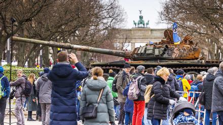 Passanten und Medienvertreter stehen in Berlin vor einem in der Ukraine zerstörten russischen Panzer. 