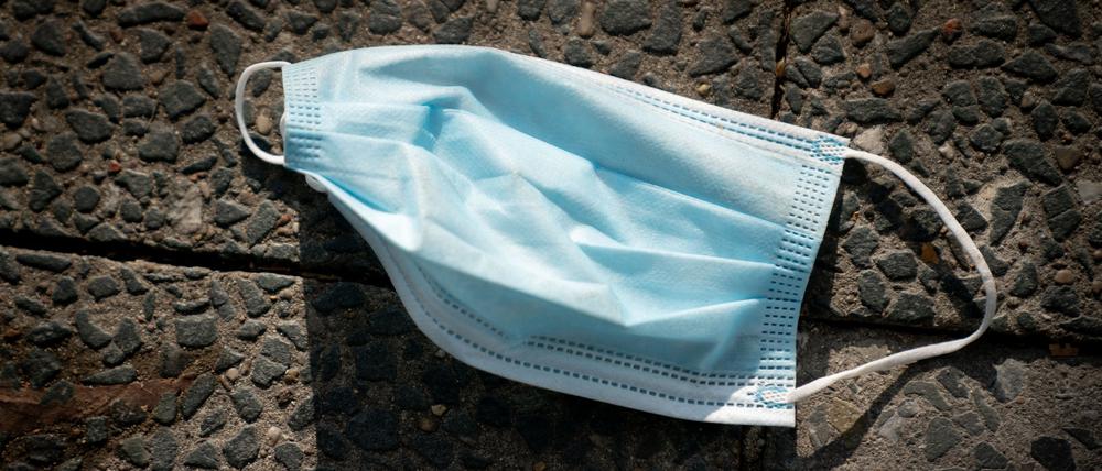 Ein Mund-Nasen-Schutz liegt auf einem Bürgersteig.