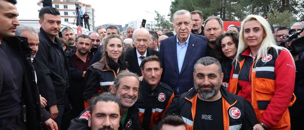 Dieses Foto zeigt den türkischen Präsidenten Recep Tayyip Erdogan (Mitte rechts) und den Vorsitzenden der nationalistischen MHP-Partei Devlet Bahceli (Mitte links), die nach dem Erdbeben vom 6. Februar, bei dem mehr als 44.000 Menschen in der Türkei und Tausende weitere im benachbarten Syrien ums Leben kamen, im Koordinierungszentrum der türkischen Katastrophenschutzbehörde (AFAD) in Adiyaman für ein Foto mit Mitgliedern der Rettungskräfte posieren.
