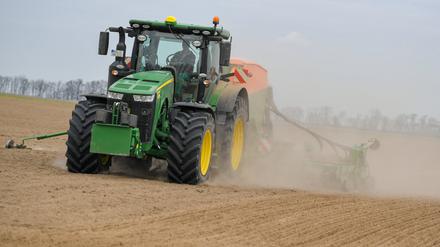 Ein Mann drillt auf einem Feld mit dem Traktor in den trockenen Boden eine Zwischenfrucht zur Bodenverbesserung. 