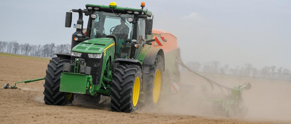 Ein Mann drillt auf einem Feld mit dem Traktor in den trockenen Boden eine Zwischenfrucht zur Bodenverbesserung. 