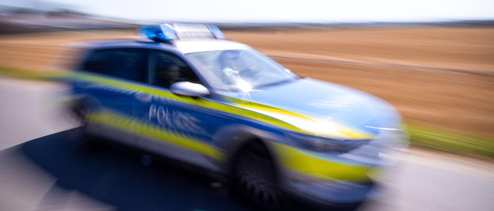 Ein Polizeiauto fährt über eine Dorfstraße.
