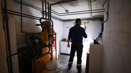 Ein Mitarbeiter eines Diesel- und Heizöl-Unternehmens prüft die Kunststofftanks in einem Heizungskeller bei der Heizöllieferung für ein Einfamilienhaus. 